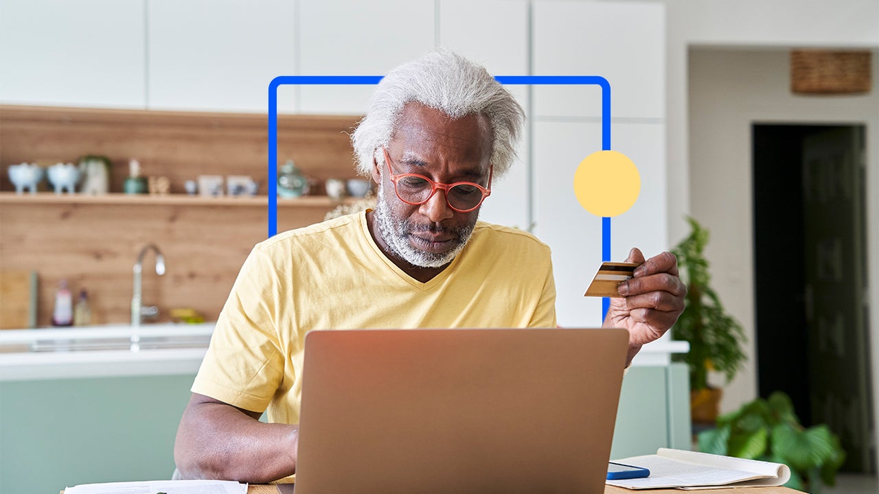 Man using laptop with credit card in hand