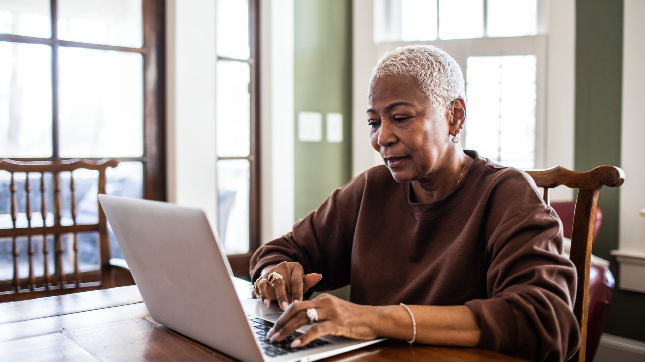 senior women sitting down and working on her laptop