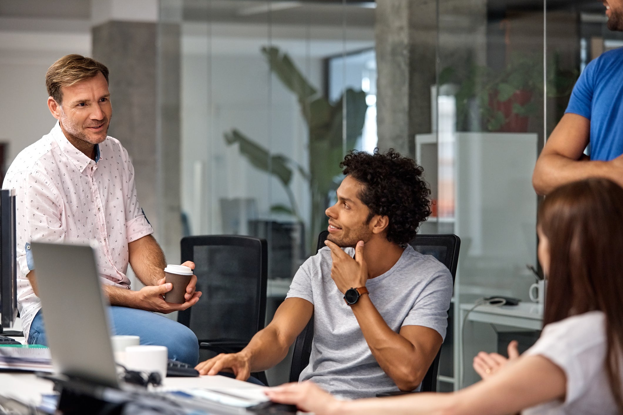 Coworkers listening to mature businessman in the office.