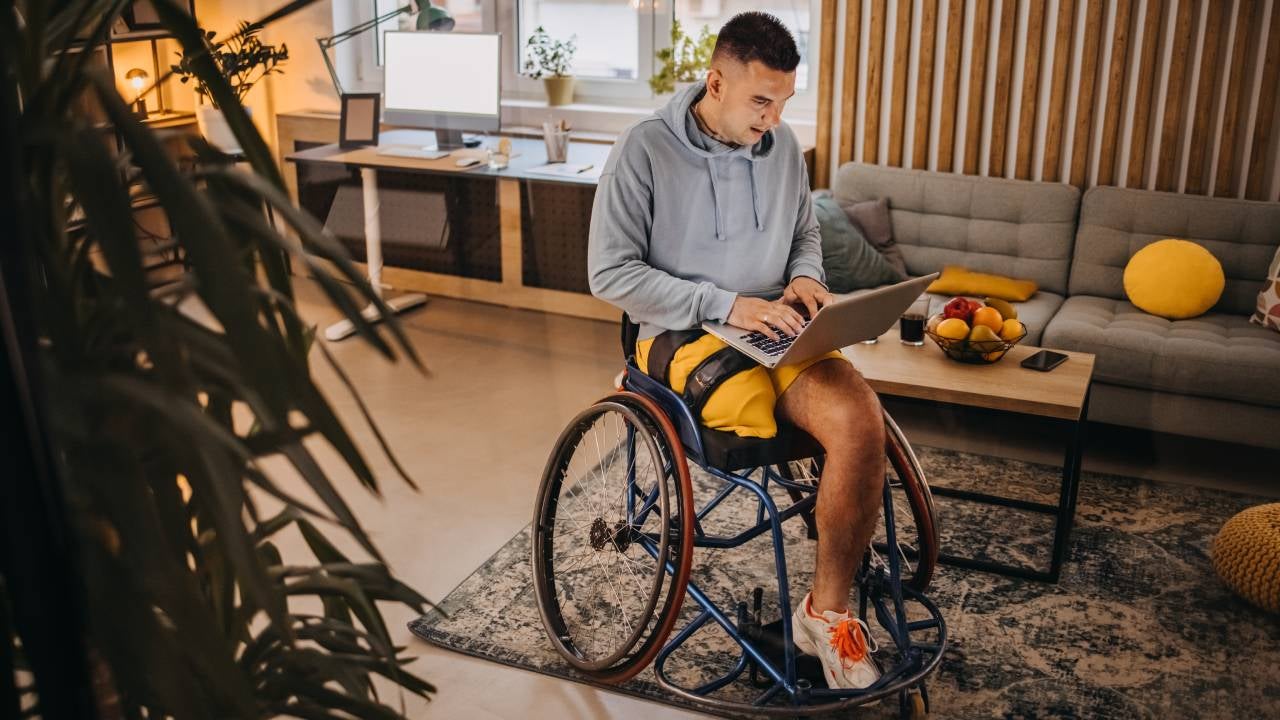 Man in wheelchair typing on laptop indoors