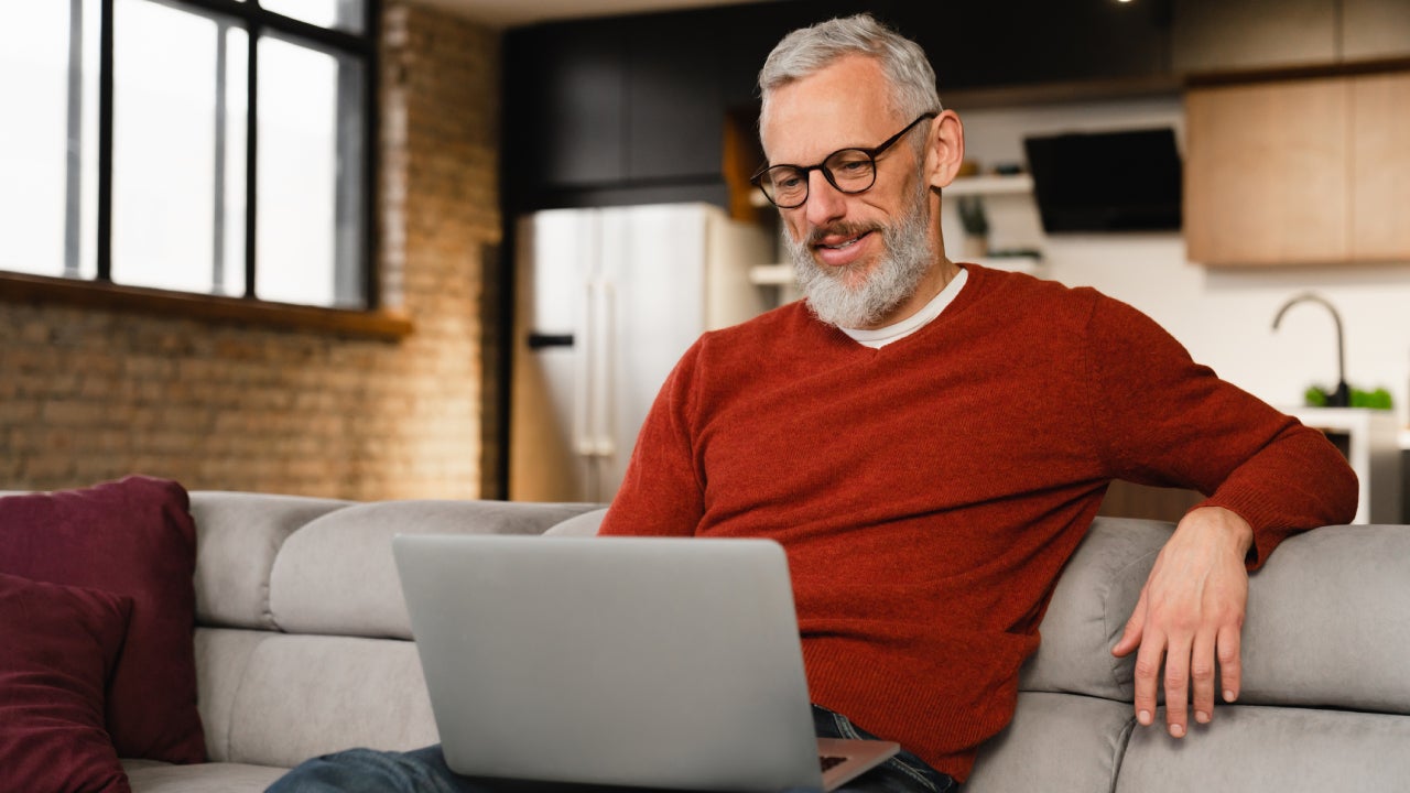 Man sitting on couch and reading laptop