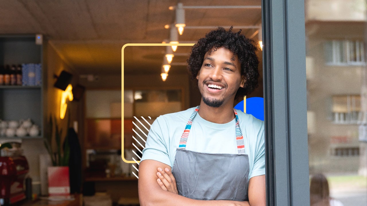 Man standing in the doorway of a business with his arms crossed.