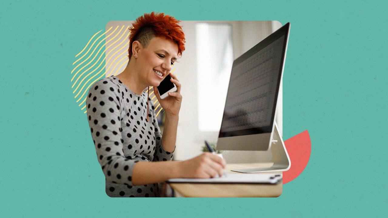 Person with short hair on the phone in front of their computer while writing something