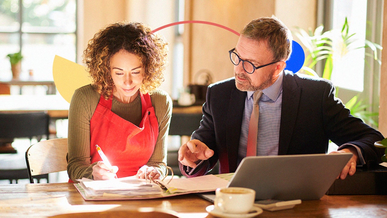 Female business owner and financial advisor review documents in a coffee shop.