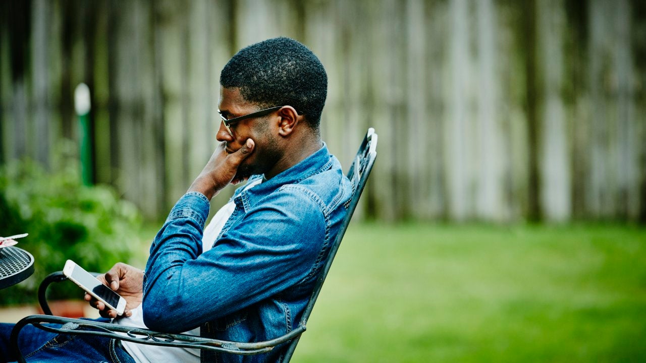 Man seated in backyard checking smartphone