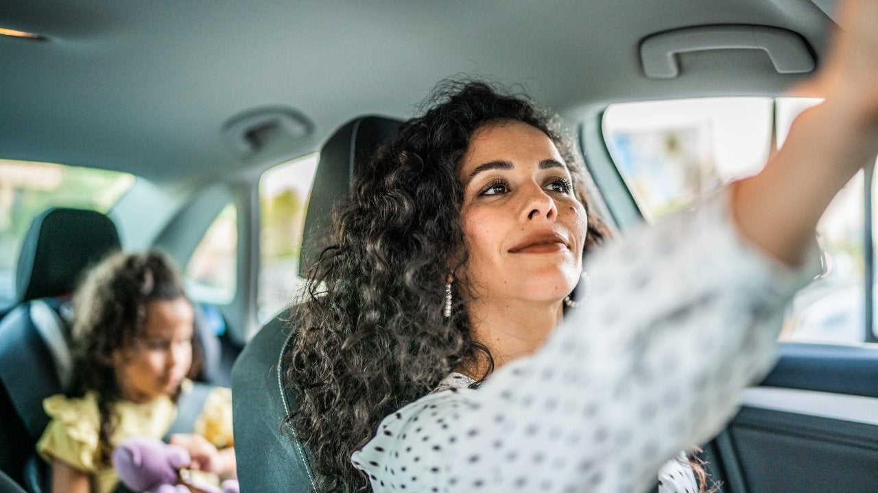 Mid adult woman adjusting rear view mirror inside a car