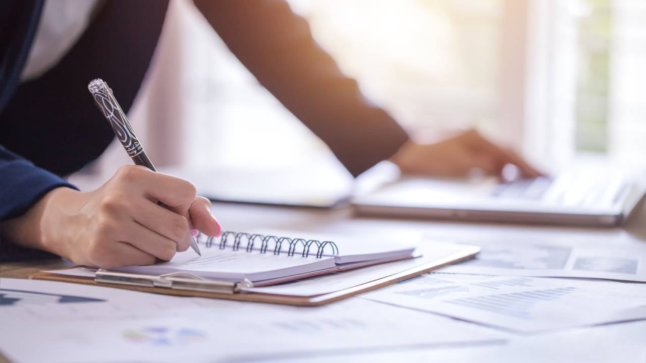 woman writing down financial information on a notepad