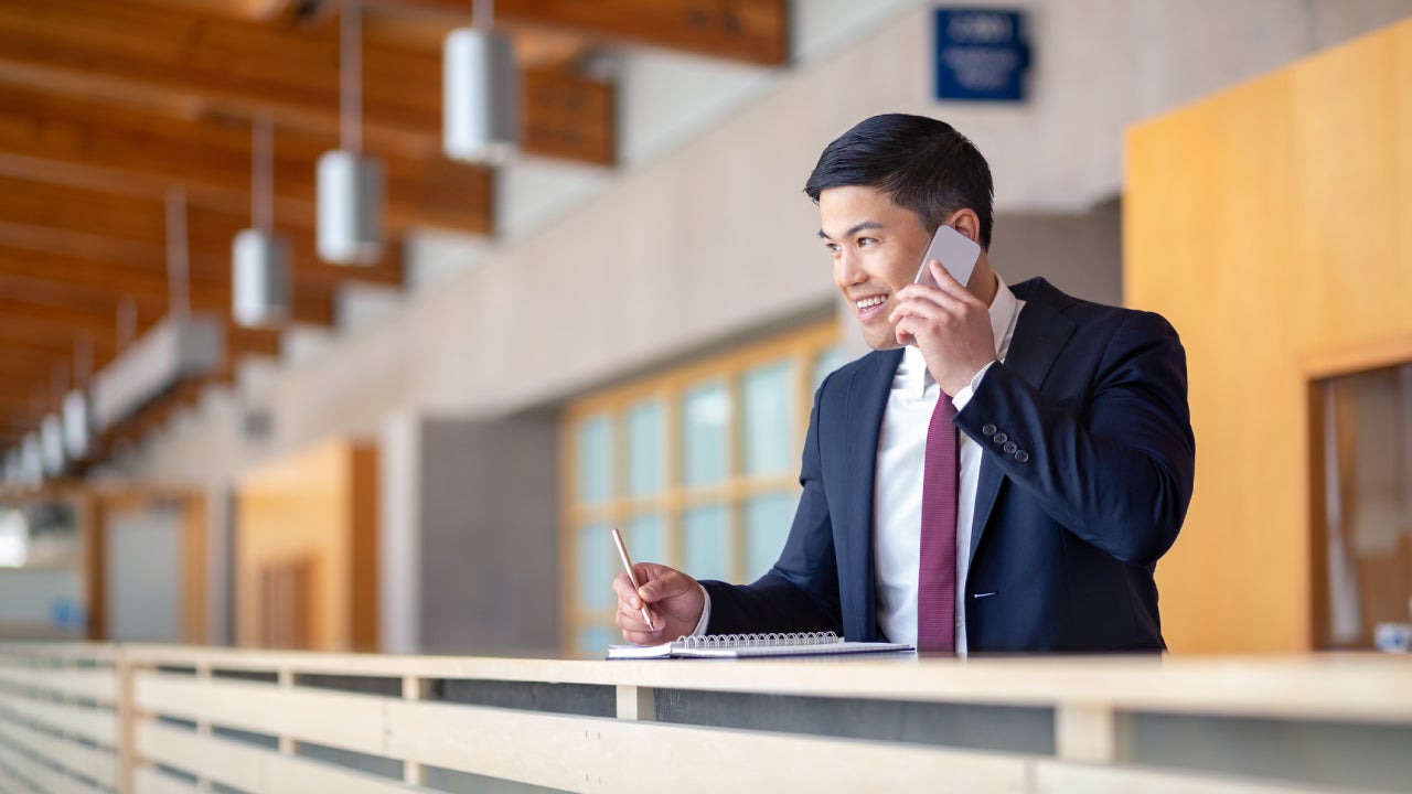 businessman talking on cellphone taking notes on note pad