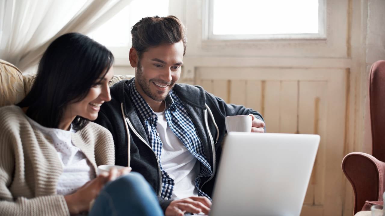 Couple looking at laptop together in their cozy loft apartment