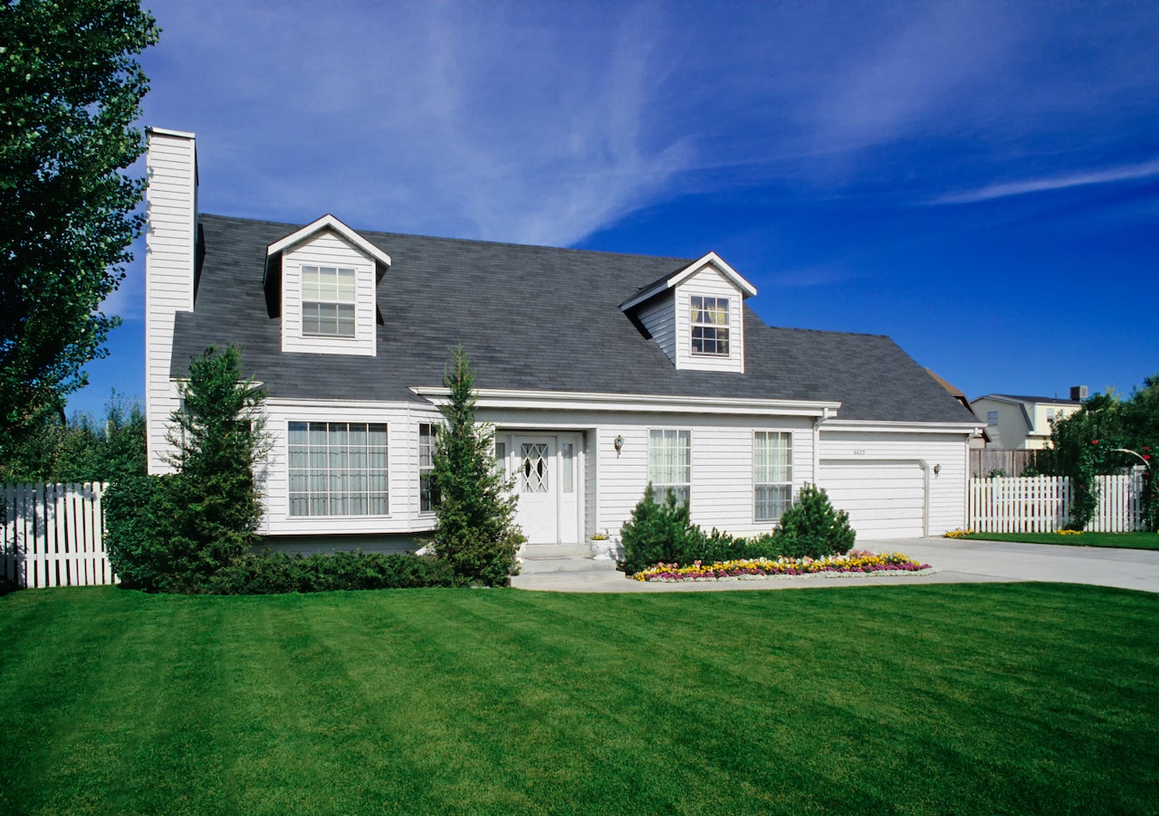 large white suburban home with green lawn and blue sky