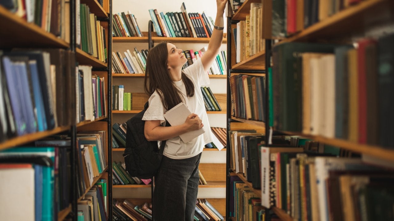 Portrait of female student looking for special book