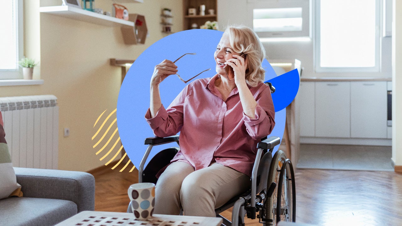 An older white woman sits in a wheelchair while talking on the phone.