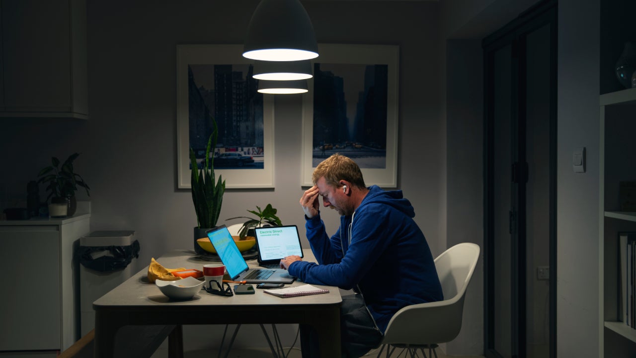 A stressed mature man goes through his home finances at the dining table