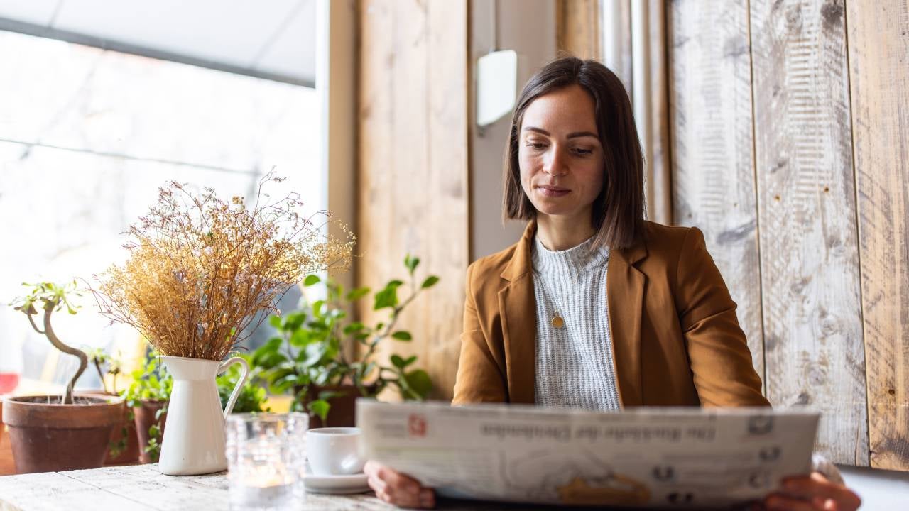 Businesswoman reading newspaper in cafe