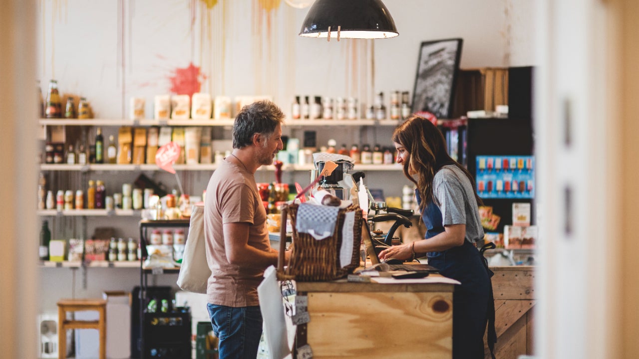 A person checks out at a register with a shop employee