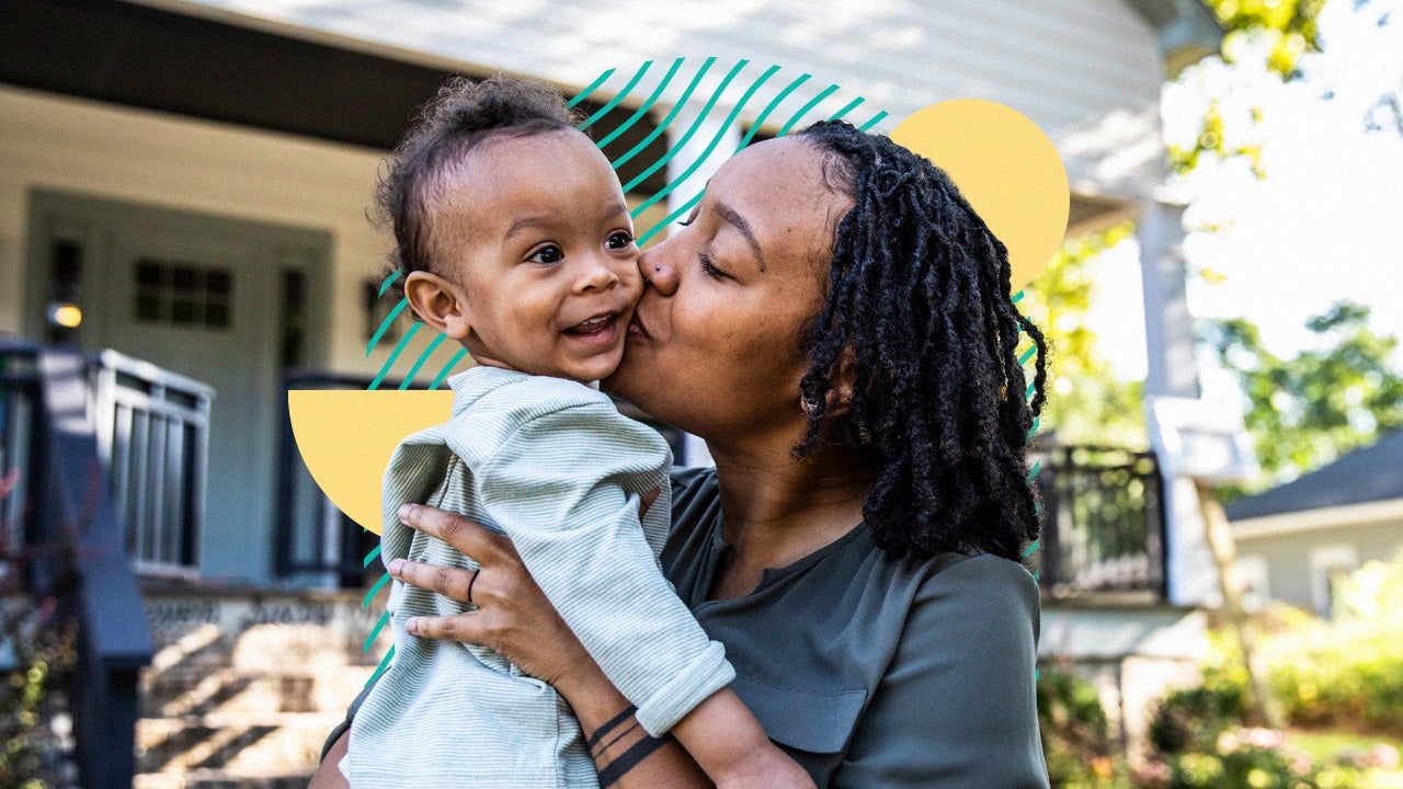 Woman kissing baby outside of house