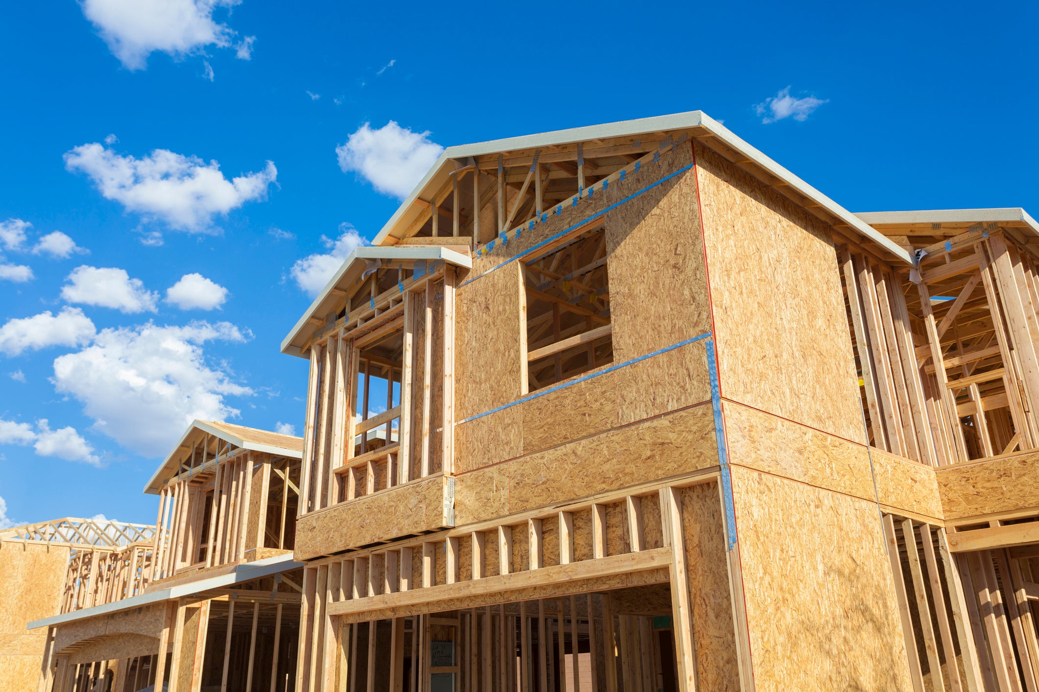 housing starts - new houses being built, wood frames against blue sky