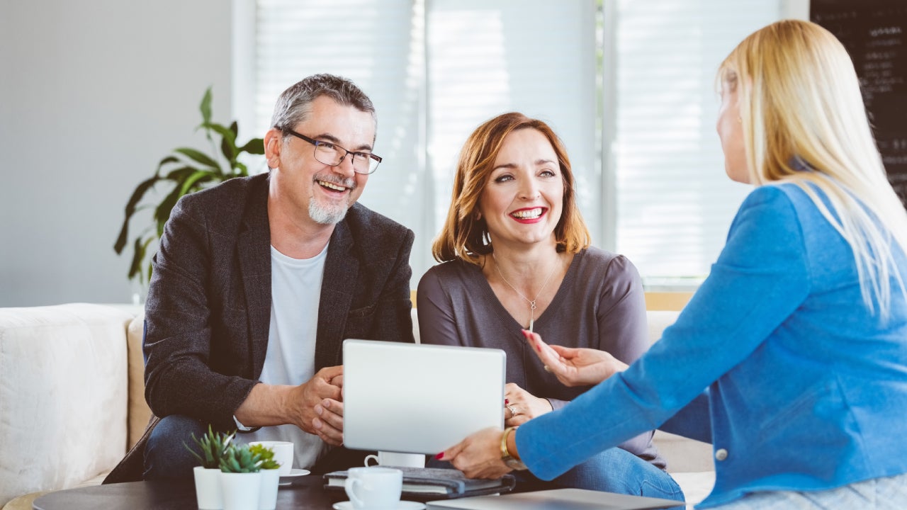 Financial advisor showing digital tablet to smiling couple at home