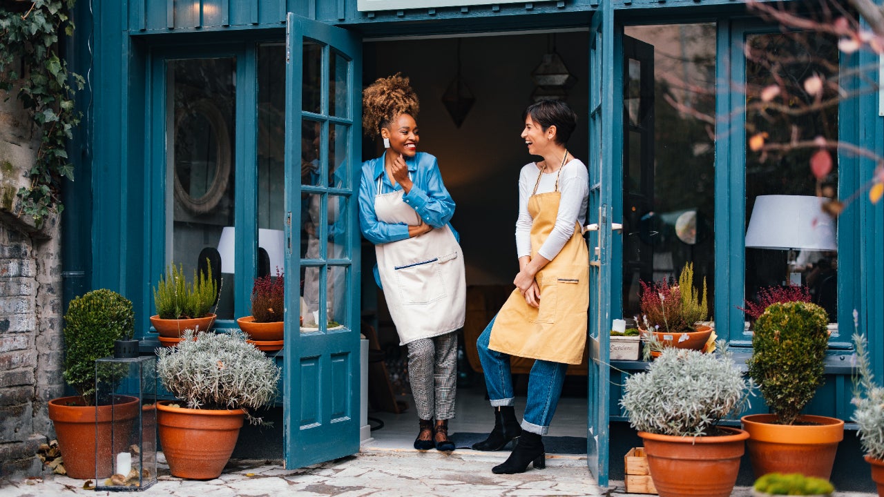 Two female business owners standing outside their shop.