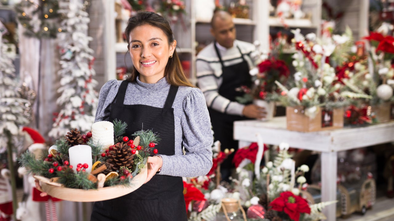 Two shop owners create festive decorations for their store.