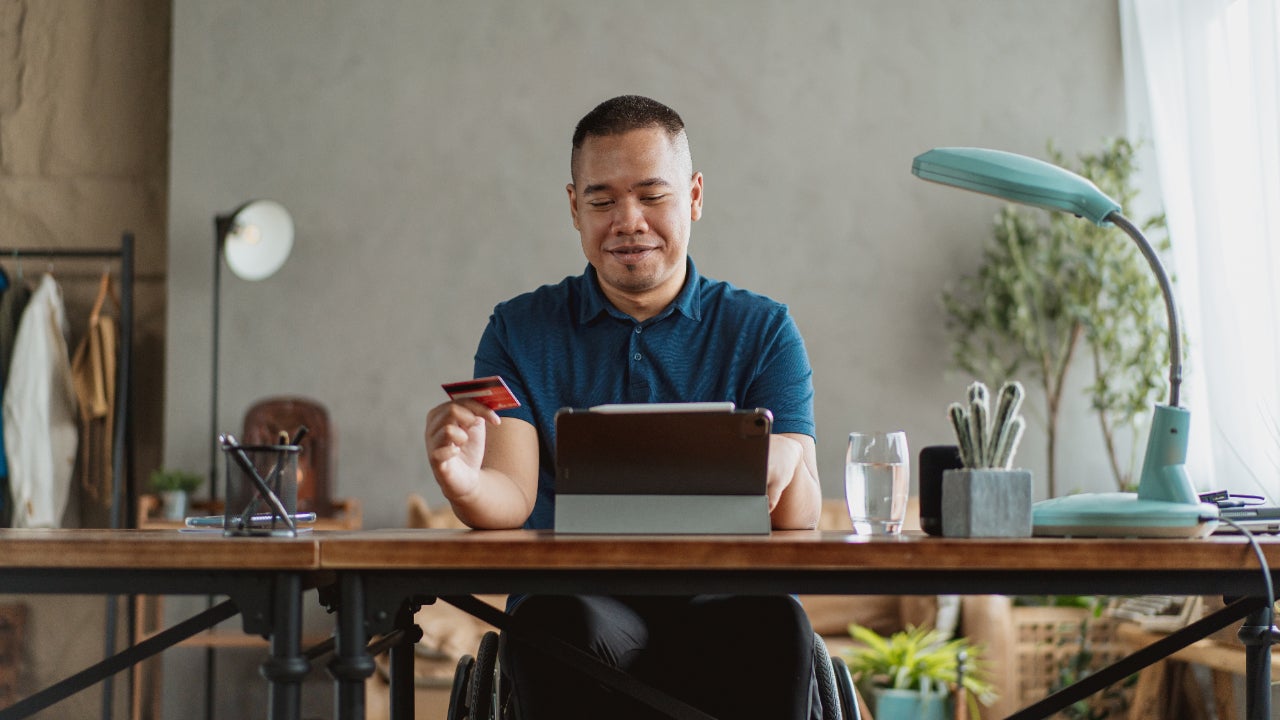 Asian man in wheelchair holding a credit card