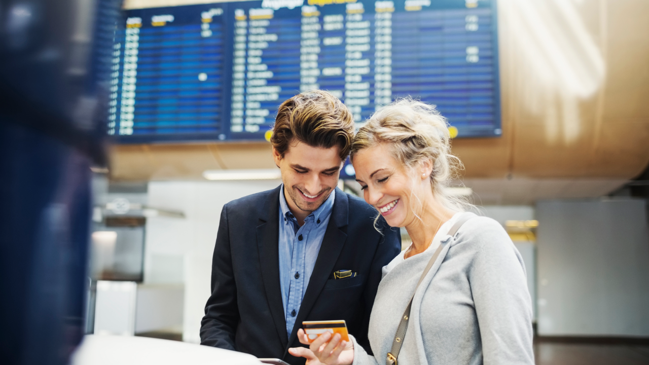 Happy business people looking at credit card in airport