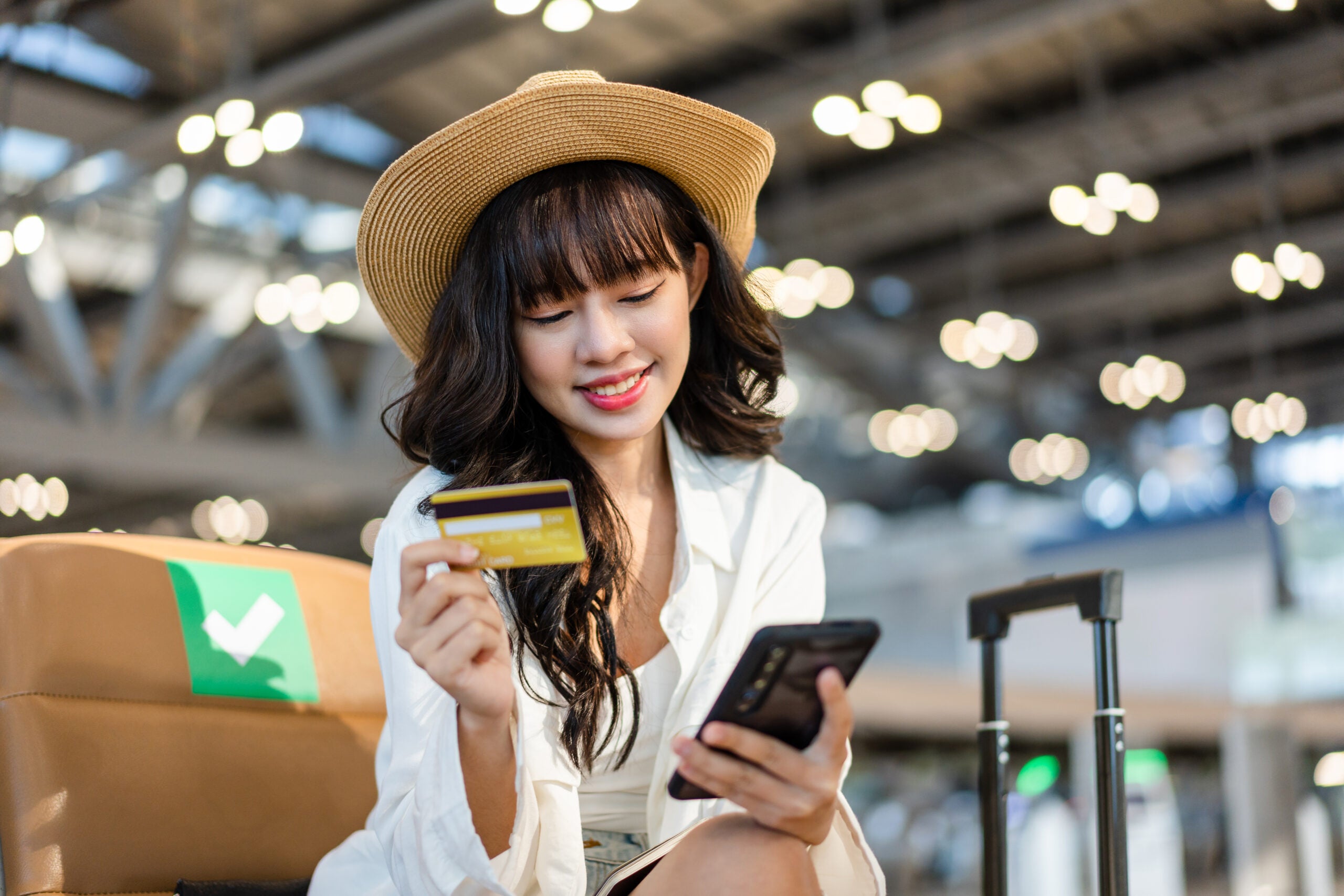 A girl using her smartphone to make a payment with a credit card.