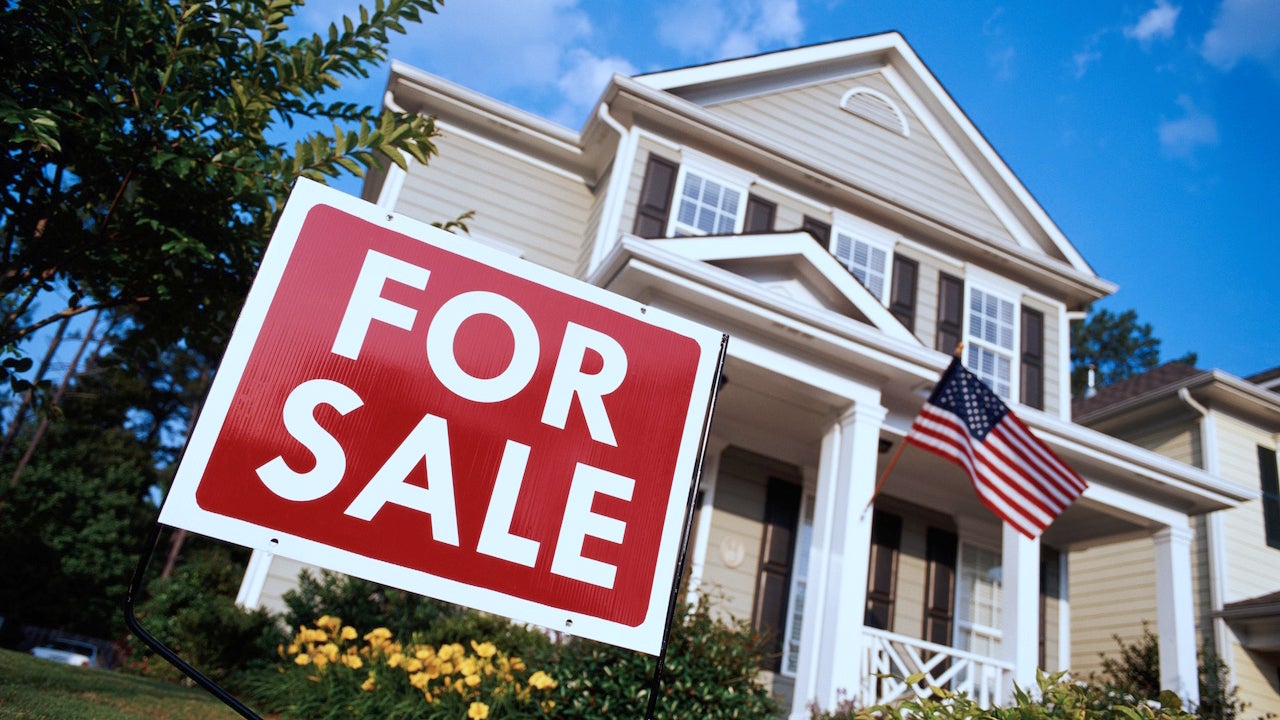 House with American flag and 'for sale' sign, low angle view