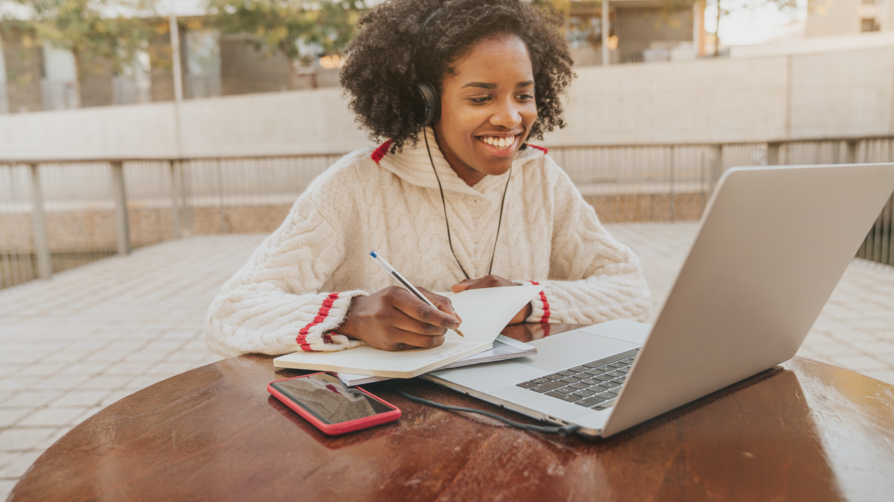 Young female student using a laptop and credit card outside on campus