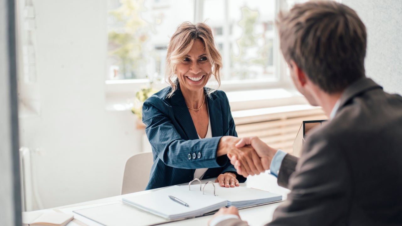 Happy businesswoman doing handshake with man at office