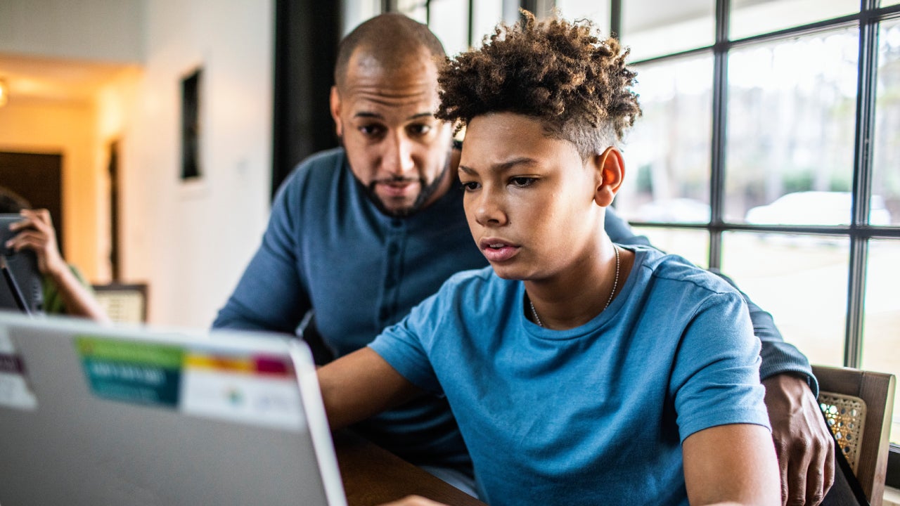 Father helping teenage son with financial planning in residential kitchen