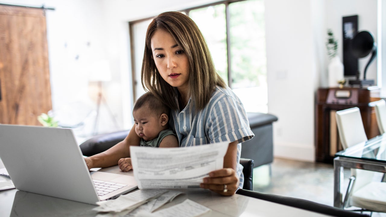 Mother holding a baby while looking at documents