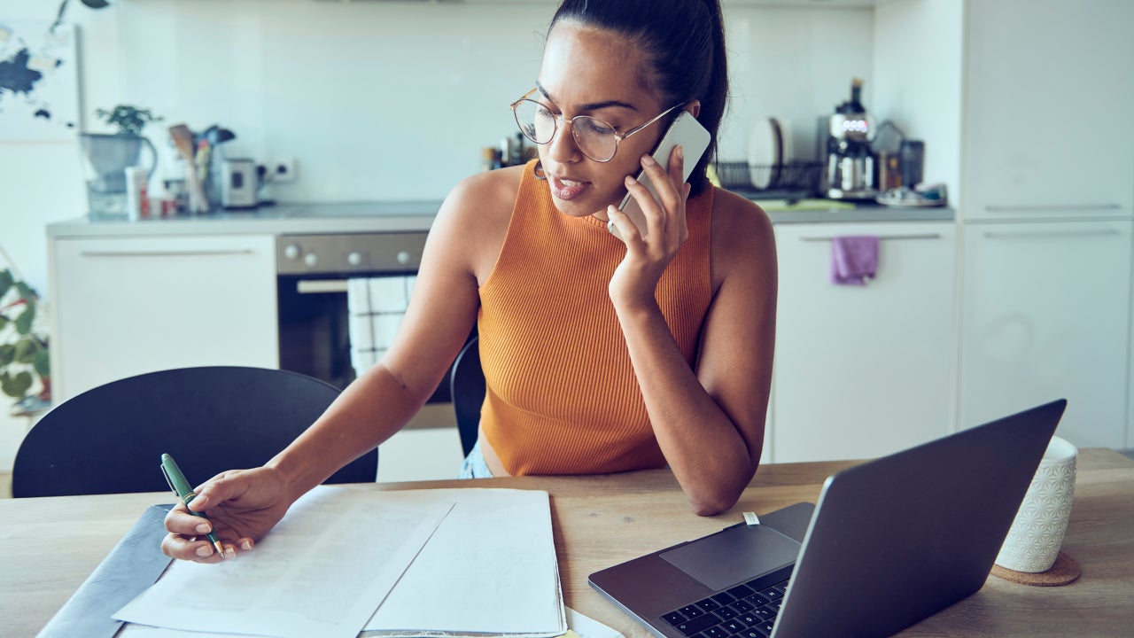 Woman using a mobile phone, laptop while working from home