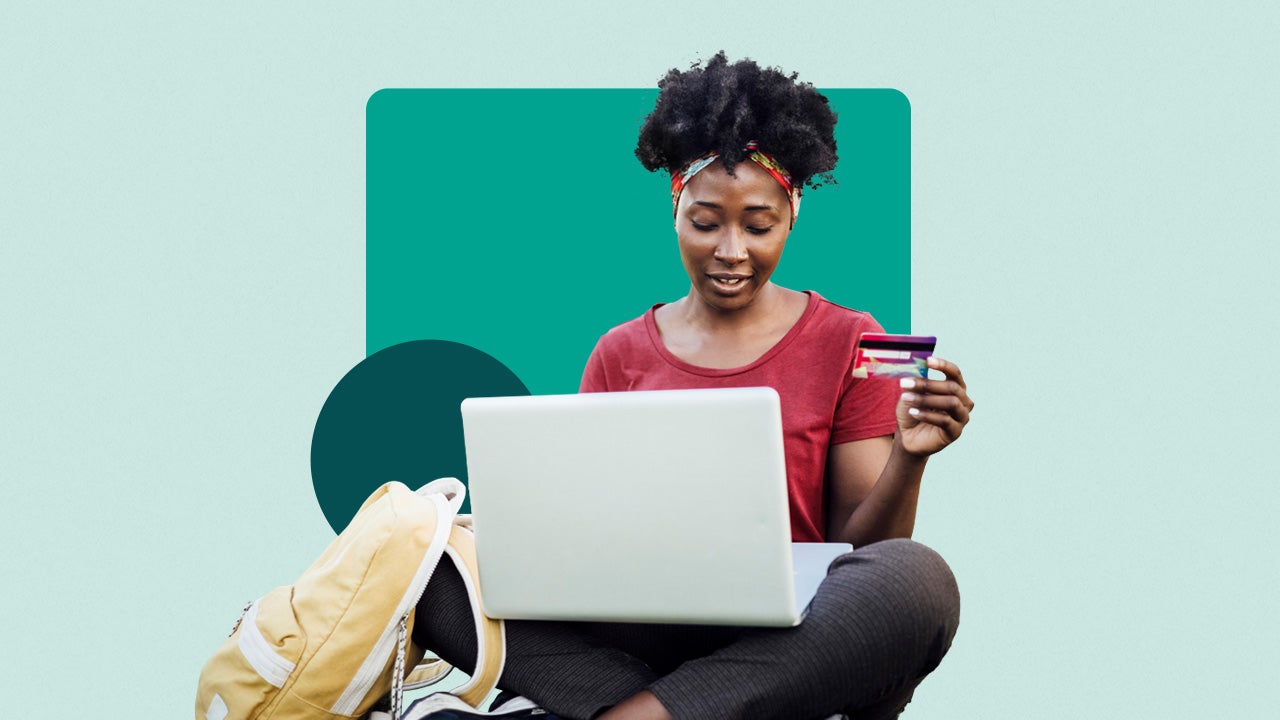 Student sitting down on her laptop while holding a credit card in one hand