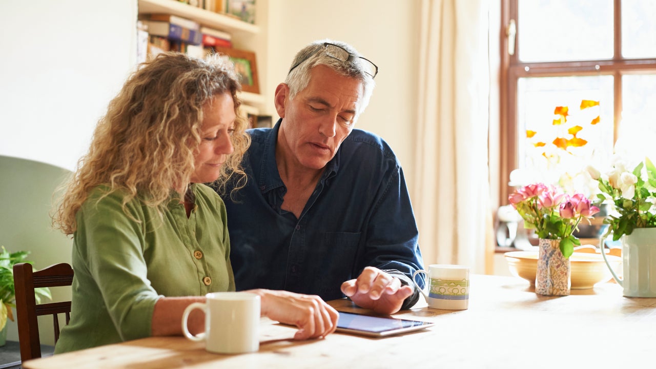 Couple sitting at table using digital tablet