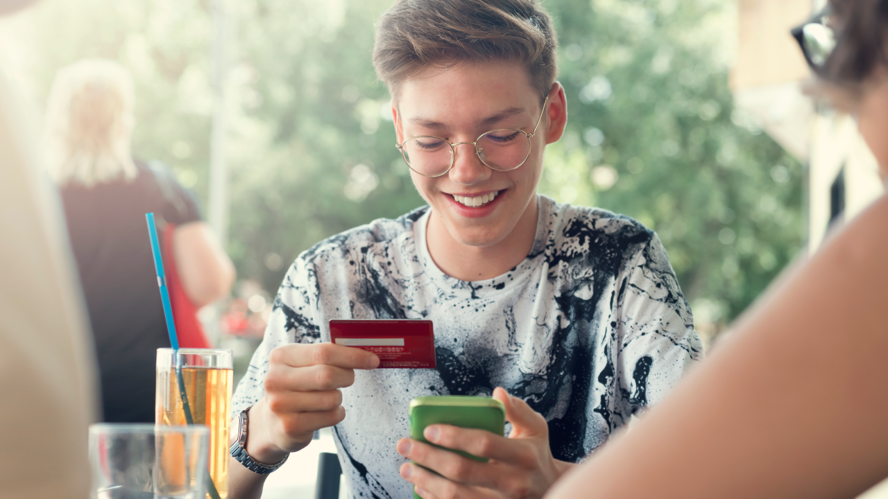 Teenager Boy and her friends Use credit card for shopping online in the cafeteria