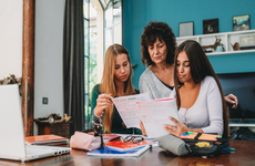 A mother and her daughters review their education cost paperwork.