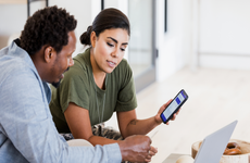 A couple discusses their finances while looking at an app.