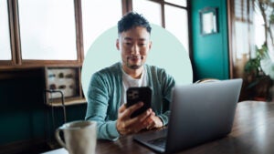 Man smiling, using a cellphone in his home office