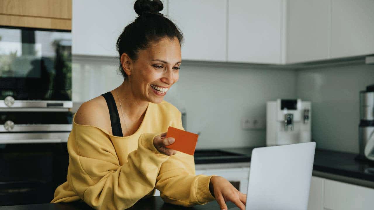 Smiling woman holding a credit card and typing on a laptop