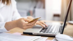 Woman using laptop and holding credit card, close-up