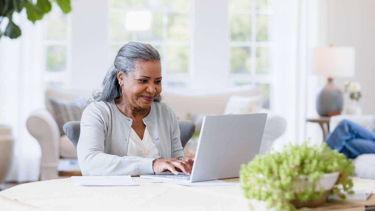 Older woman sits at her computer answering emails.