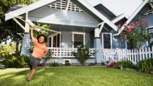 Boy with toy airplane in front yard of house