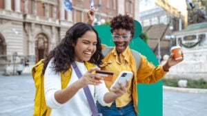 design image of two woman smiling and one is holding a credit card and phone in her hand