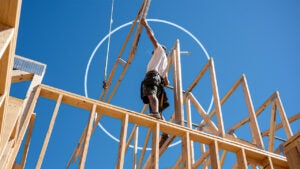 Construction worker standing on lumber frame of new house being built