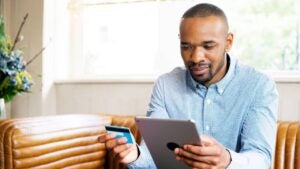 Black man holding credit card and tablet