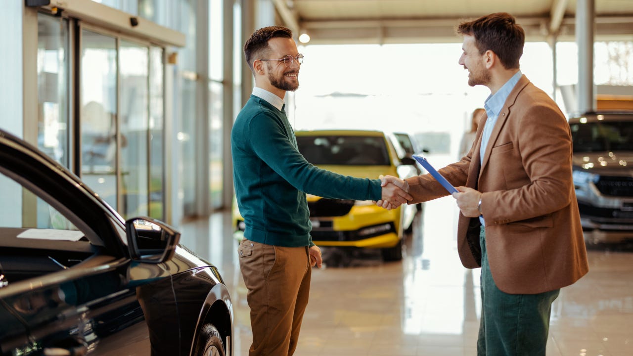 Two people shaking hands at a dealership