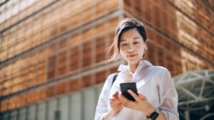 A woman looks at her phone outside.