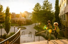 Two university students walk down campus stairs