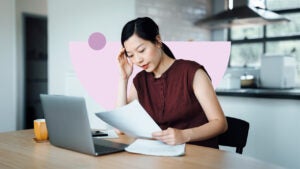 Woman studying a document and working on a laptop